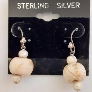 May include: Sterling silver earrings with white, round, textured beads. The earrings are on a black card with the text "STERLING SILVER".
