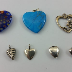 May include: A collection of ten heart-shaped pendants, including a blue glass pendant with a floral pattern, a turquoise stone pendant, a silver pendant with a floral design, a silver pendant with a keyhole, a silver pendant with a beaded border, a silver leaf pendant, a silver heart pendant, a silver heart pendant with a closed lid, a silver heart pendant with a closed lid, and a silver heart pendant.