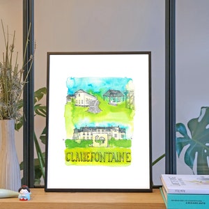May include: A watercolor illustration of a building with the text "CLAIRE FONTAINE" printed below. The illustration is framed in a black frame and is displayed on a wooden shelf with a vase of dried flowers and a book.