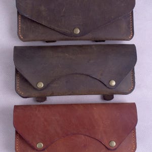 Una billetera de cinturón de cuero, un porta tarjetas de presentación, una billetera y un teléfono inteligente para conductores, ciclistas y simplemente personas que usan solo pantalones cortos y una camiseta.
