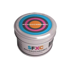 Peut inclure: Une boîte en étain argentée avec un motif de cible bleu, rose et orange sur le couvercle. Le texte "HYDROCHROMIC" est imprimé sur le couvercle. Le texte "#HYDROCHROMIC" et "COLOUR CHANGING" est imprimé sur le côté de la boîte.