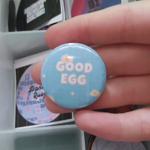 Insignia de botón de 25/32 mm con fondo de cuadrícula azul y meme "Buen huevo saludable"