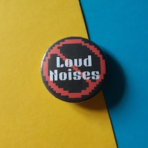 May include: A black and red button with a diagonal red line through it and the text "Loud Noises" in white.