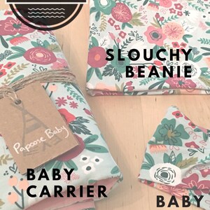 May include: A set of three sewing patterns for a baby carrier, a slouchy beanie, and a headband. The patterns feature a floral print with pink, red, and green flowers on a light blue background. The text "Papoose Baby Co. Sewing Patterns" is on a brown circle with white text. The text "Slocuhy Beanie", "Baby Carrier", and "Baby Headband" are in black text.