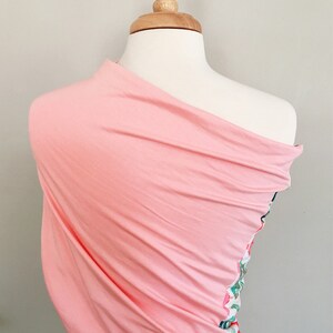 May include: A pink fabric wrap with a floral pattern on one side. The wrap is draped over a white mannequin.