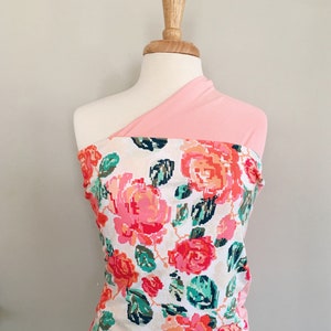 May include: A pink and white floral fabric with a pink solid fabric overlay. The fabric is draped over a mannequin.