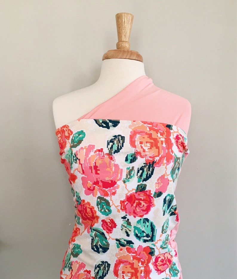 May include: A pink and white floral fabric with a pink solid fabric overlay. The fabric is draped over a mannequin.