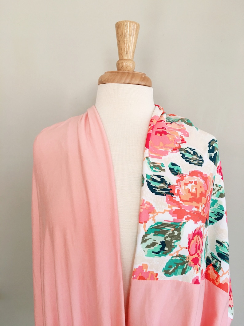 May include: A pink and white floral fabric with a pink solid fabric on the other side. The fabric is draped over a white mannequin.