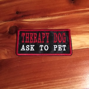 May include: Black and red embroidered patch with white text that reads "Therapy Dog Ask To Pet".