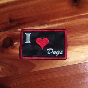 May include: Black embroidered patch with red heart and white text that says "I love Dogs".