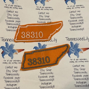 May include: Two orange embroidered patches in the shape of Tennessee, with the number "38310" stitched in the center. The patches have a white border and are displayed on a white background with floral and text elements.