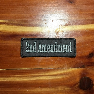 May include: Black embroidered patch with white text that reads "2nd Amendment".