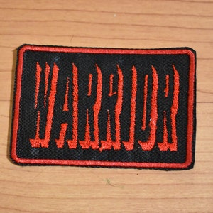 May include: Red embroidered patch with the word "WARRIOR" in a bold, stylized font on a black background.