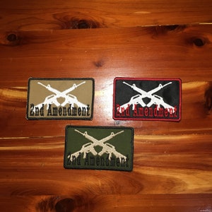 May include: Three embroidered patches with the text "2nd Amendment" and a pair of crossed rifles. The patches are in tan, black, and green.