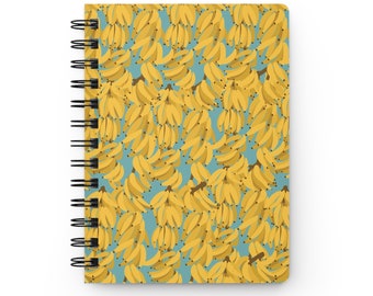 Puede incluir: Una libreta de espiral con una cubierta amarilla y azul con un patrón repetitivo de racimos de plátanos amarillos.