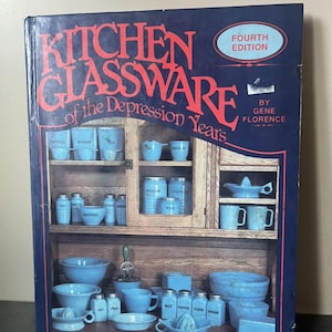 Könnte beinhalten: Buchcover mit dem Titel "Kitchen Glassware of the Depression Years" mit blauem und rotem Design. Das Cover zeigt eine Illustration eines Holzschranks, der mit blauen Glaswaren gefüllt ist, darunter Schalen, Tassen und Gläser.