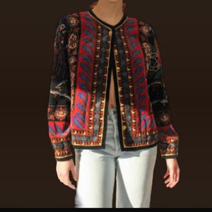 Puede incluir: Una chaqueta de punto negra, roja y azul con estampado. La chaqueta tiene un diseño geométrico con detalles florales.