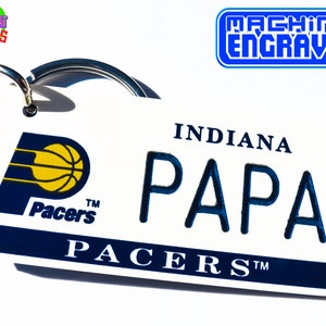 May include: White keychain with a blue and yellow Indiana Pacers logo and the text "Indiana Papa Pacers TM" in blue lettering.