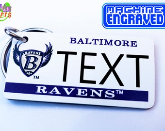 May include: White and blue Baltimore Ravens keychain with a metal ring. The keychain features the Ravens logo with the team name and the words "Baltimore" and "Ravens" in blue text.