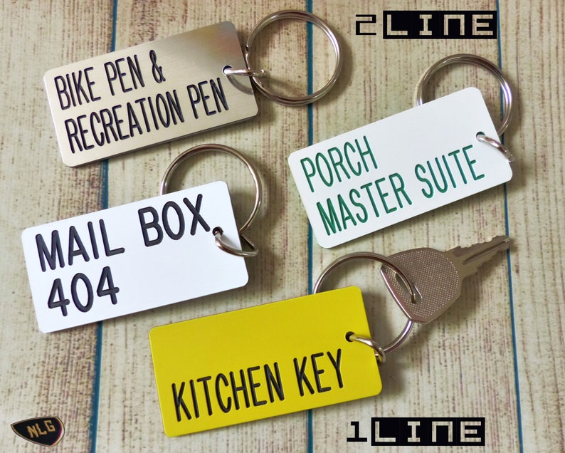 May include: Four rectangular metal keychains with split rings. One silver tag reads BIKE PEN & RECREATION PEN, one white tag reads PORCH MASTER SUITE, one white tag reads MAIL BOX 404, and one yellow tag reads KITCHEN KEY with a metal key attached.