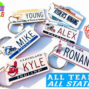 May include: A collection of personalized keychains featuring different sports team logos and state names. The keychains are white with colorful accents and feature names like "Mike", "Alex", "Ronan", and "Kyle". The keychains are made in the USA.