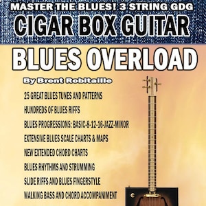 May include: A book titled "BLUES OVERLOAD" by Brent Robitaille, featuring a cigar box guitar. The cover includes text about blues tunes, riffs, progressions, charts, rhythms, and fingerstyle techniques. The book has over 330 pages and is published by kalymi publishing.