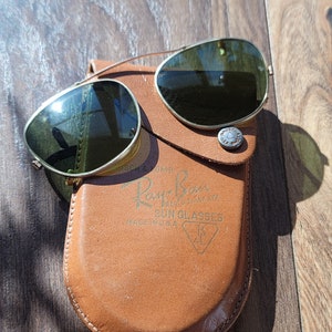 Green glass with gold tone metal frames. Aviator style clip on glasses.  Clips are covered with beige tone plastic/rubber material.