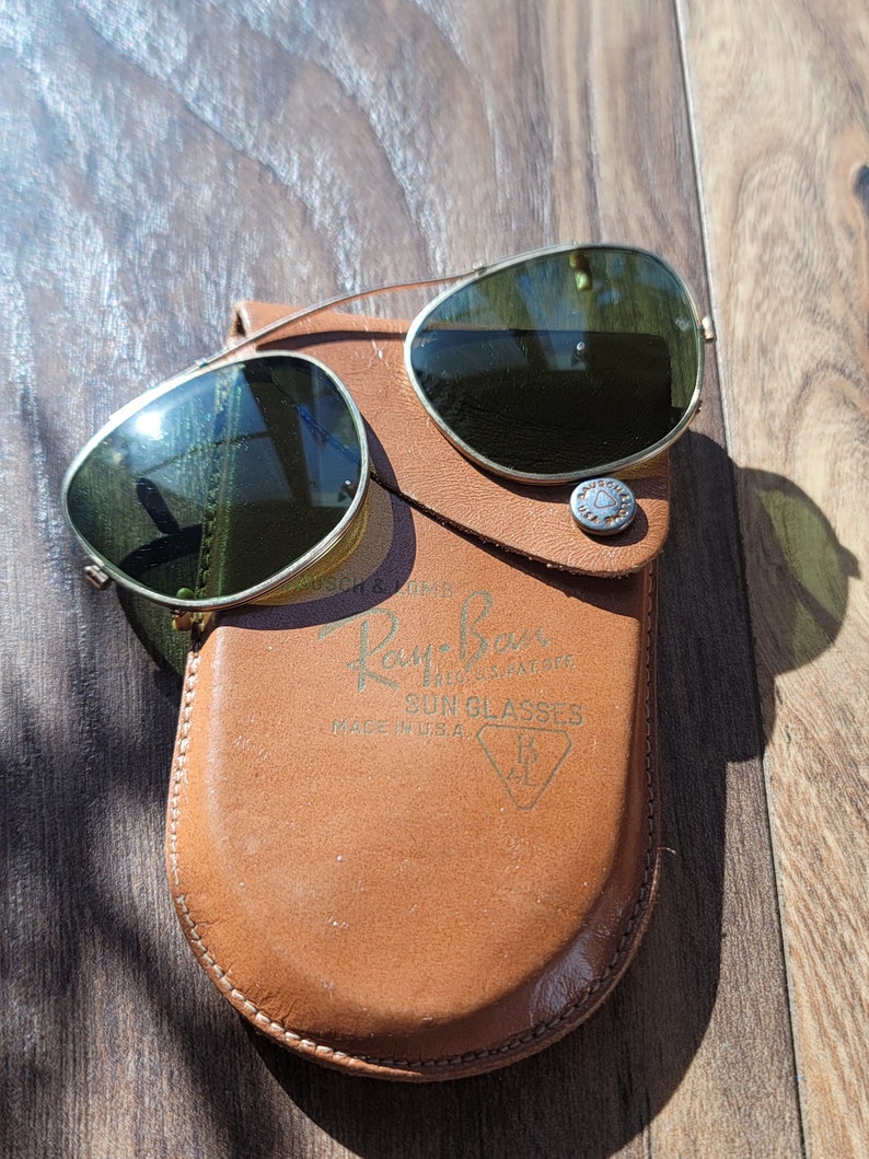 Green glass with gold tone metal frames. Aviator style clip on glasses.  Clips are covered with beige tone plastic/rubber material.