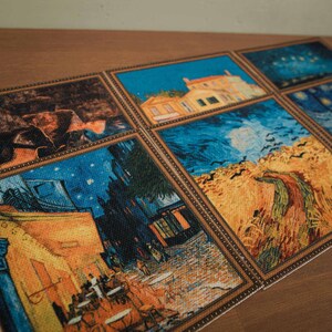 May include: A set of six framed coasters featuring famous paintings by Vincent van Gogh. The coasters are made of a woven fabric with a textured surface. The paintings include "Starry Night", "The Cafe Terrace at Night", "Wheatfield with Crows", and "The Yellow House".
