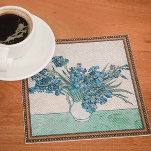 Puede incluir: Un posavasos cuadrado con un borde dorado presenta una pintura de un jarr&oacute;n de iris azules sobre un fondo verde.