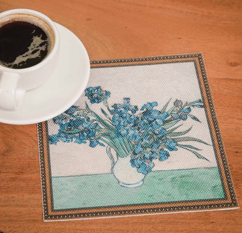 Puede incluir: Un posavasos cuadrado con un borde dorado presenta una pintura de un jarr&oacute;n de iris azules sobre un fondo verde.