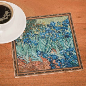 Puede incluir: Un posavasos cuadrado con una imagen enmarcada de una pintura de iris azules con hojas verdes. El posavasos tiene un fondo marr&oacute;n con un borde dorado.