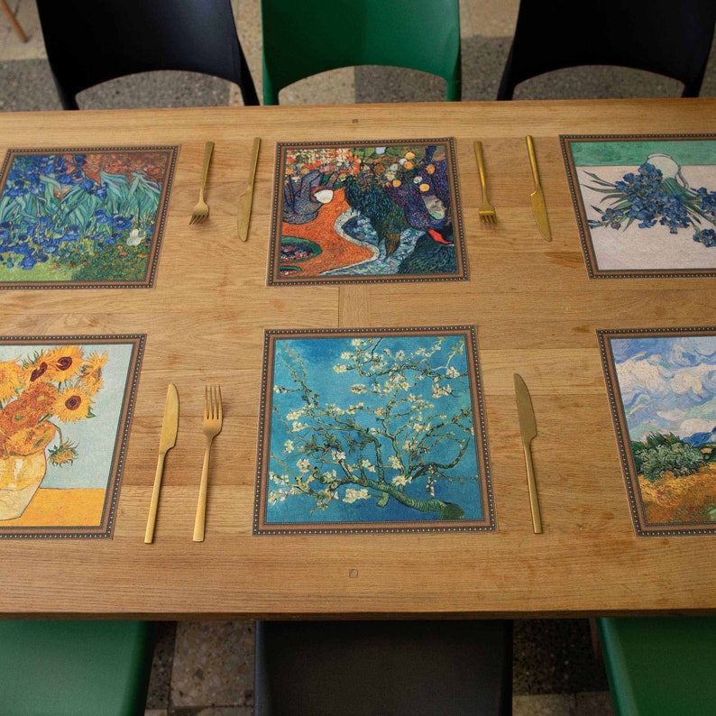 Puede incluir: Una mesa de madera con seis cubiertos, cada uno con una pintura famosa diferente impresa en un mantel individual. Los manteles individuales est&aacute;n enmarcados con un borde dorado. Cada cubierto incluye un tenedor y un cuchillo dorados.