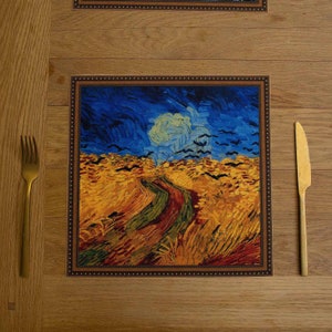 May include: A brown wooden table setting with a placemat featuring a painting of a field with a winding path and a blue sky. The painting is framed with a brown border. A gold fork and knife are placed on the table.