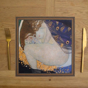 May include: A framed print of a painting depicting a nude woman with long red hair, sitting with her legs bent and her arms wrapped around her body. The background is a dark blue with gold and white accents.