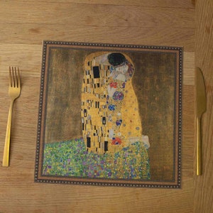 May include: A placemat featuring a reproduction of Gustav Klimt's "The Kiss" painting. The painting depicts a couple embracing in a golden mosaic style.