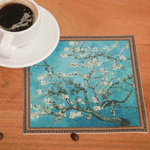 Puede incluir: Un posavasos azul y blanco con una imagen enmarcada de un almendro en flor. El posavasos tiene un borde decorativo.