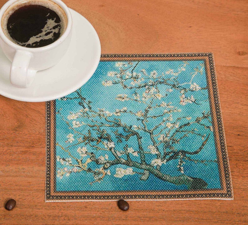 Puede incluir: Un posavasos azul y blanco con una imagen enmarcada de un almendro en flor. El posavasos tiene un borde decorativo.
