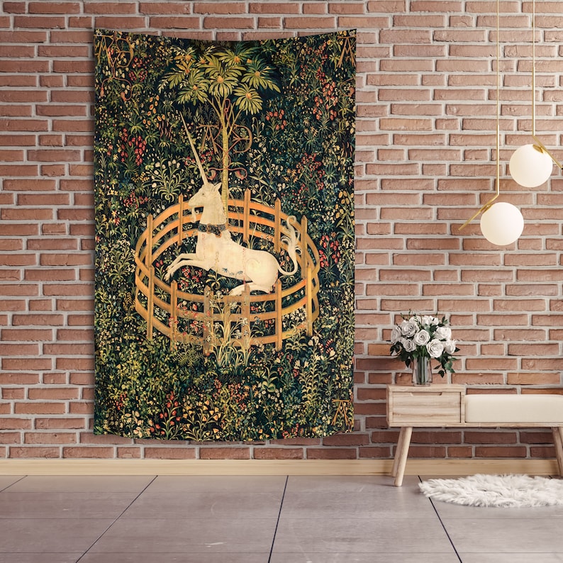 May include: A tapestry featuring a white unicorn trapped in a circular fence, surrounded by a lush green forest with colorful flowers and foliage.