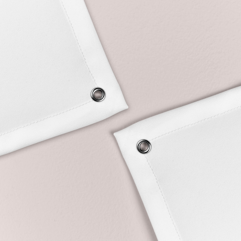 May include: Two white fabric shower curtains with silver eyelets at the top corners.