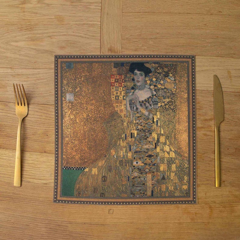 May include: A gold and brown placemat with a framed image of a woman in a gold dress. The image is a mosaic of small squares and rectangles, creating a textured effect.