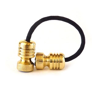 Puede incluir: Dos juguetes de fidget de metal dorado conectados por una banda elástica negra. Los juguetes tienen un diseño acanalado y se utilizan para aliviar el estrés.