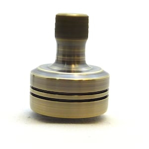 May include: A brass spinning top with a rounded top and two grooves around the middle.