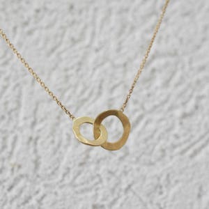 May include: A gold chain necklace with a pendant featuring two interlocking circles.