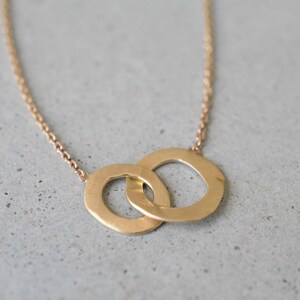 May include: A gold necklace with a pendant featuring two interlocking circles.