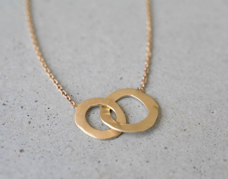 May include: A gold necklace with a pendant featuring two interlocking circles.
