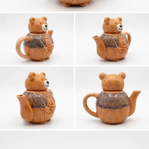 Może przedstawiać: Ceramiczny czajniczek w kształcie pluszowego misia ubranego w niebieską kamizelkę, trzymającego koszyk z owocami. Głowa misia pełni funkcję pokrywki, którą można zdjąć, aby odsłonić otwór. Czajniczek posiada dzióbek oraz uchwyt po prawej stronie.