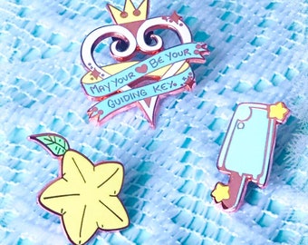 May include: Three enamel pins featuring characters from the Kingdom Hearts video game series. The first pin is a pink heart with a crown and a banner that reads "May your heart be your guiding key". The second pin is a yellow starfruit. The third pin is a blue keyblade.