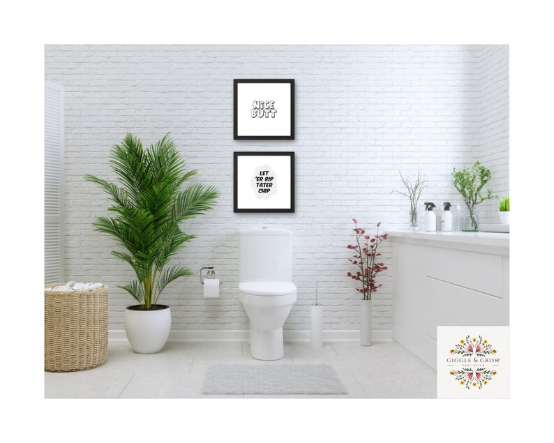 May include: Two framed prints with white text on a black background hang on a white brick wall in a bathroom. The top print says "Nice Butt" and the bottom print says "Let Yer Drip  Fatter Chip".