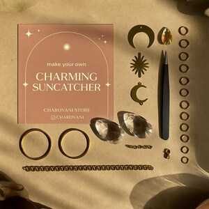 Peut inclure: Un kit de fabrication de capteur de soleil comprenant une carte carrée avec le texte 'make your own CHARMING SUNCATCHER', des breloques en métal doré en forme de croissant et d'étoile, des cristaux transparents, une pince noire et des anneaux.